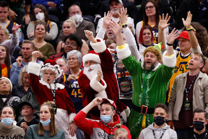Fans raise their arms in the air while dressed as an elf and santas
